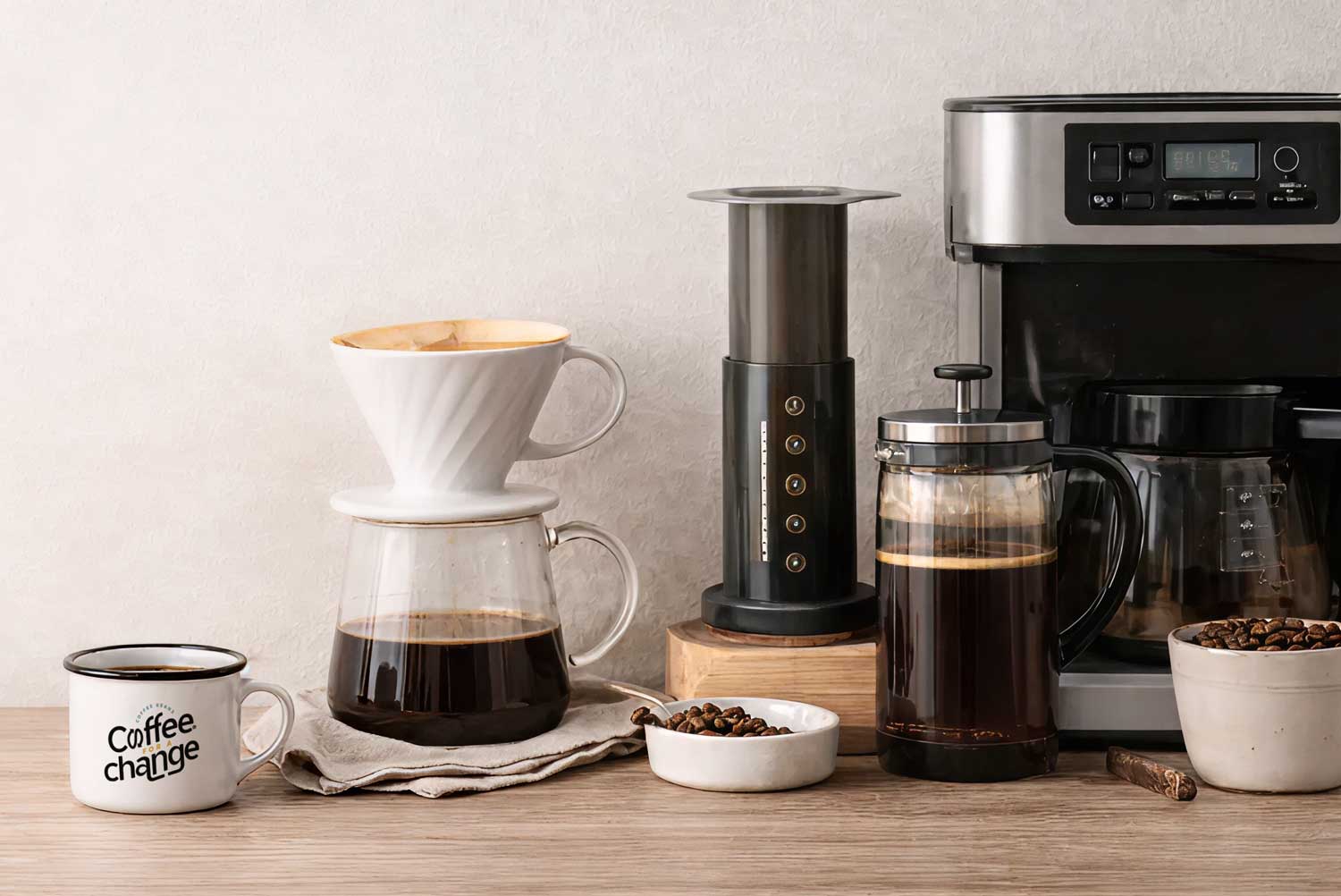 Coffee brewing setup with enamel mug, pour over dripper, French press, AeroPress, and drip coffee machine