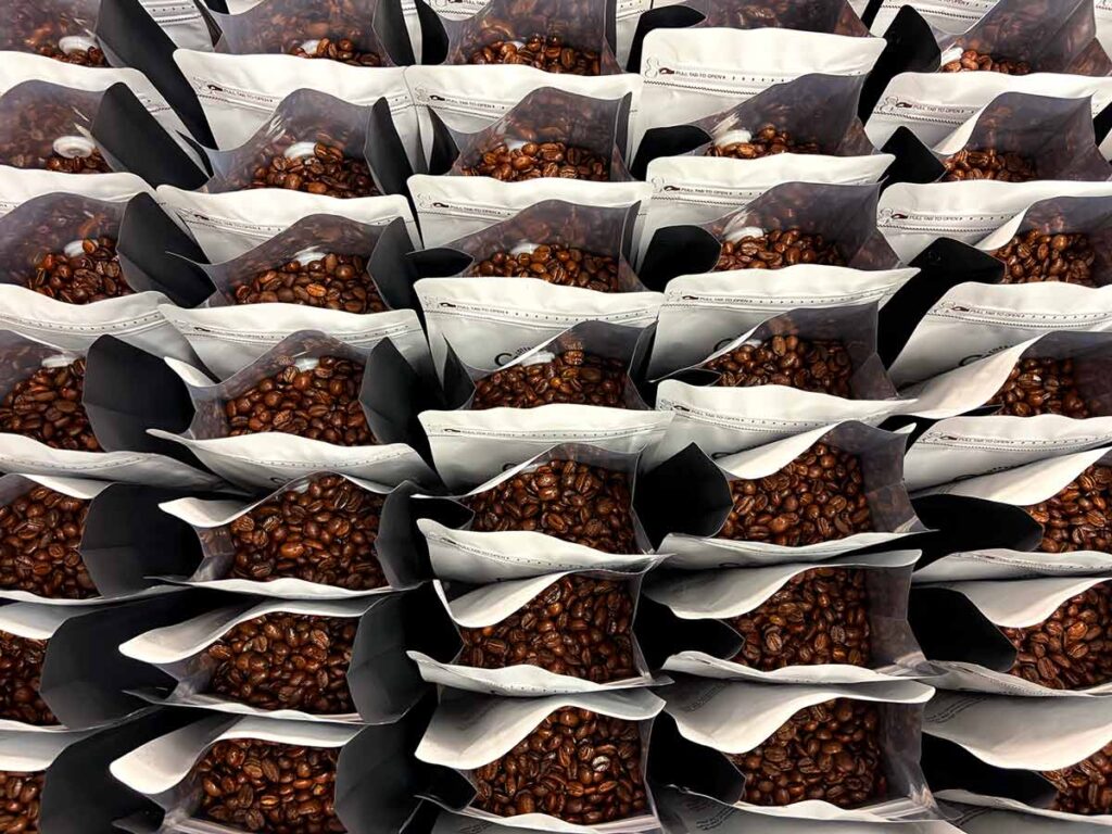 Coffee bags being filled during packaging process, showing freshly roasted beans prepared with care and consistency